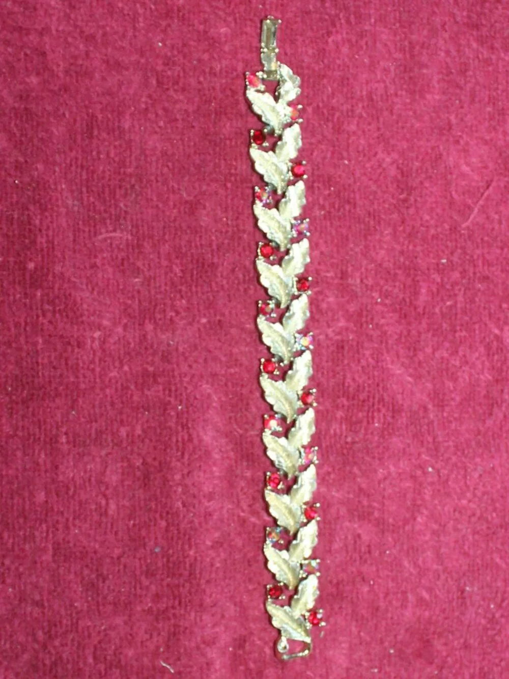 Coro vintage bracelet features a gold-tone leaf design adorned w/red rhinestones
